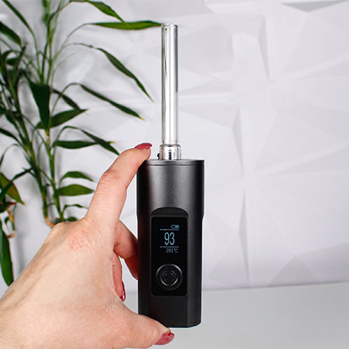 Hand holding an Arizer Solo 2 Max vaporizer with a clear glass stem and illuminated digital display.