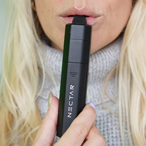 Woman in the process of using the Nectar Hex vaporizer.