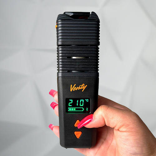 Hand holding a Venty vaporizer with a digital display showing 210°C, battery level, and orange control buttons.