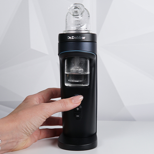 Dr. Dabber Switch 2 on a table while woman is pressing a power button