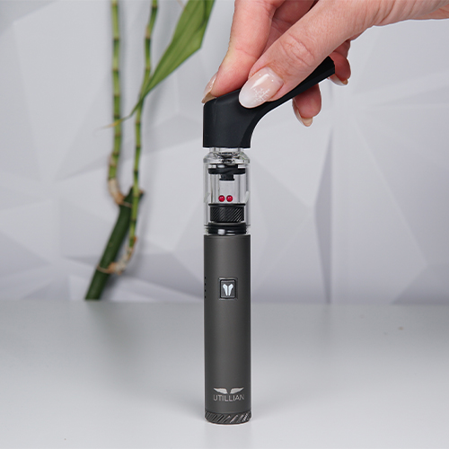 Utillian 6 dab pen on a table while woman is attatching its extended mouthpiece